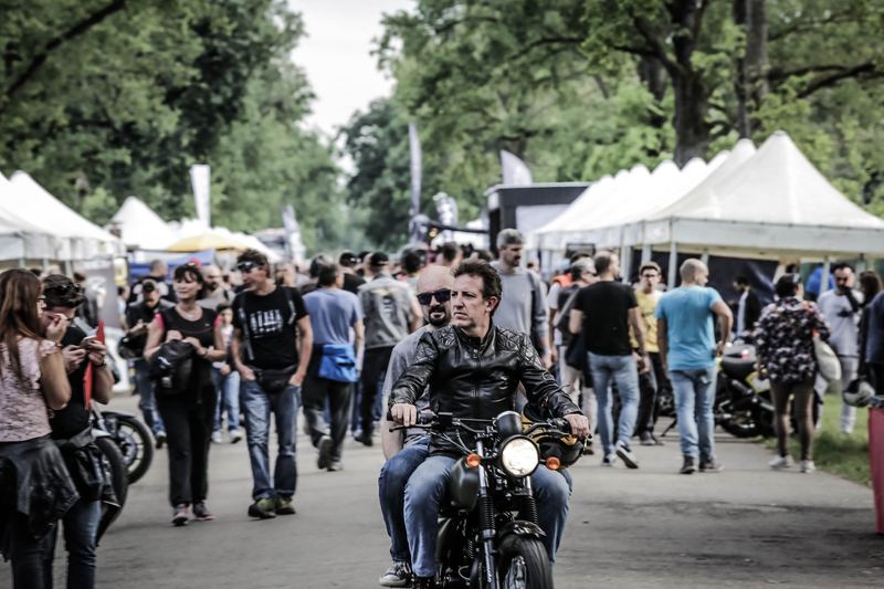 Motociclista che attraversa la folla del paddock