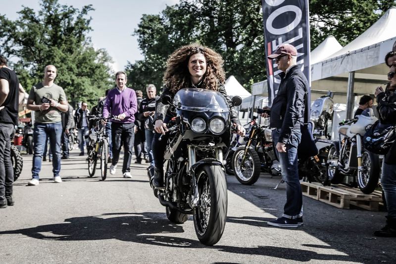 Ragazza riccia in moto tra la gente