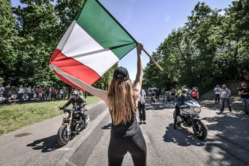 Tricolore al vento, due moto pronte, cielo blu