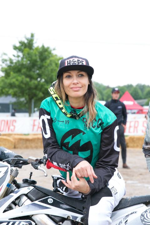 Pilota donna in maglia verde, sorridente in griglia