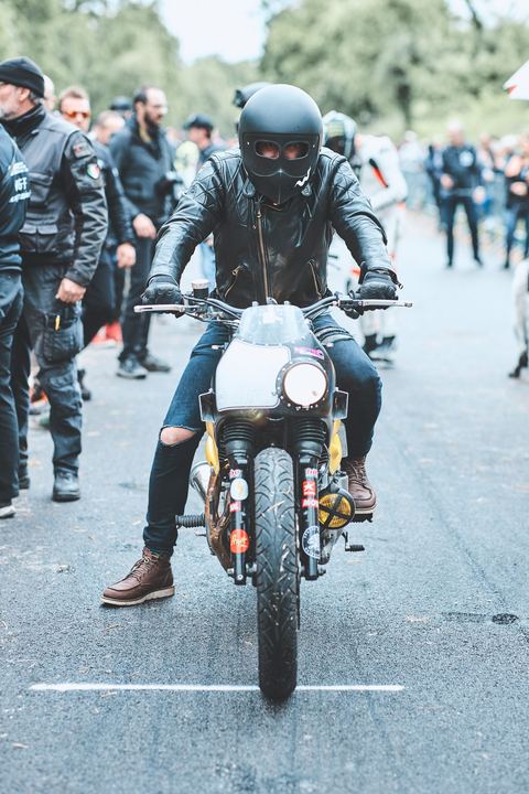 Cafe racer carenata sulla linea bianca tra la gente